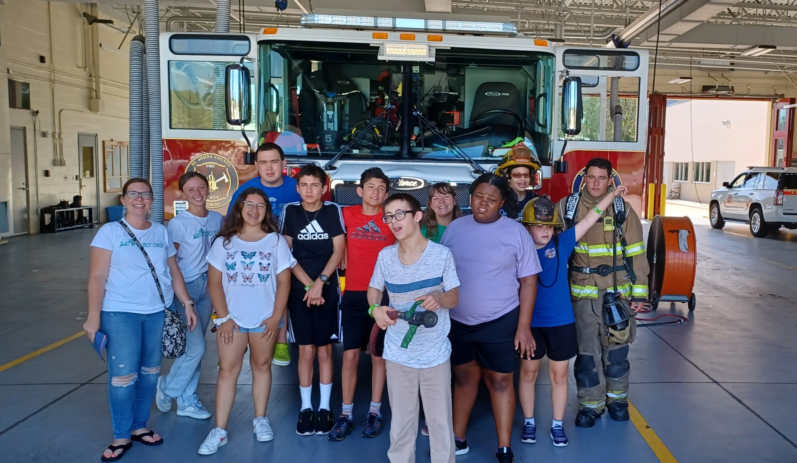 several youth & fire fighters standing in front of a fire truck